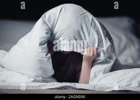 Angst Kind versteckt unter Decke isoliert auf Schwarz Stockfoto