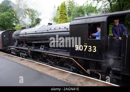 Krieg Abteilung Sparmaßnahmen 2-8-0 schwere Fracht Dampflok Nr. 90733 mit Treiber und Feuerwehrmann in der Kabine, am Bahnhof warten Oxenhope, Yorkshire GROSSBRITANNIEN Stockfoto