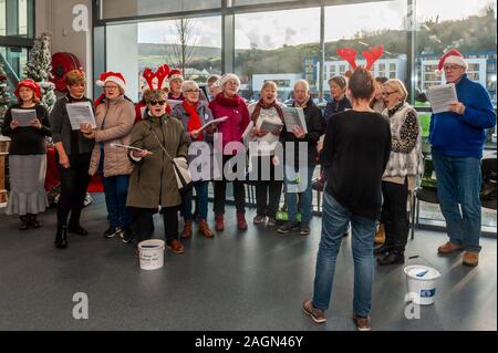 Bantry, West Cork, Irland. 20 Dez, 2019. Bantry Gemeinschaft Chor statt eine improvisierte Performance in einem Supermarkt in Bantry heute. Sie verbrachten Zeit zu Fuß rund um die Shop unterhaltsam die Käufer durch singen Weihnachtslieder. Credit: Andy Gibson/Alamy Leben Nachrichten. Stockfoto