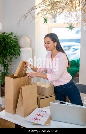 Gut aussehende junge Frau im Beutel mit Geschenken suchen Stockfoto