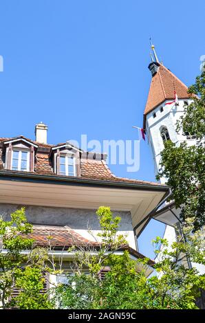 Die Stadtkirche Thun und Gebäude im historischen Zentrum von Thun, Schweiz. Die Reformierte Kirche hat einen schönen mittelalterlichen Turm und einem barocken Gang. Schweizer touristische Sehenswürdigkeit. Vertikale Foto. Stockfoto