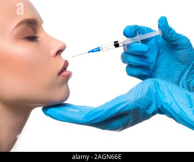 Zugeschnittenes Bild von Doctor's Hände in Latex Handschuhe Injektion mit Spritze zu Woman's Lippen isoliert auf Weiss. Stockfoto