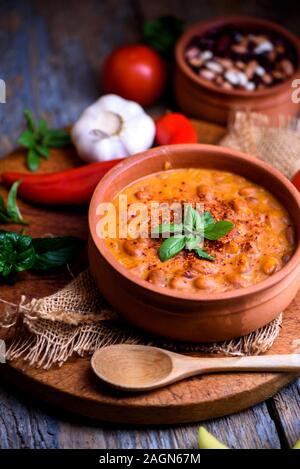 Traditionelle gebackene Bohnen in Tomatensoße in retro Tontopf mit Gewürzen und Gemüse gekocht. Hausgemachte gesunde Küche. Stockfoto