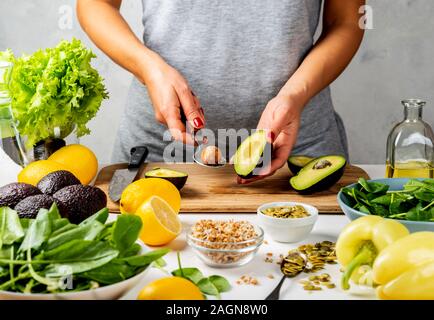 Frau Zubereitung Avocado für das Essen in der Küche. Kochen gesund essen Konzept Stockfoto