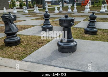 Ein Außenbereich Riesenschach auf Zement und Gras Quadrate mit Stühlen im Hintergrund für die Wiedergabe von Wettbewerben closeup Stockfoto