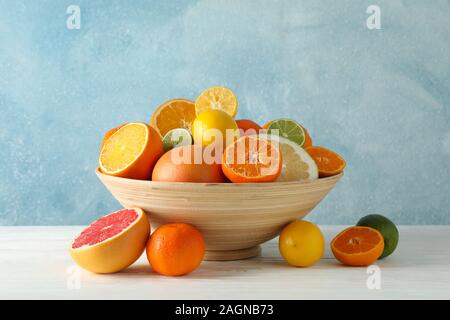 Saftige Zitrusfrüchte in Schale auf holztisch vor blauem Hintergrund, Platz für Text Stockfoto