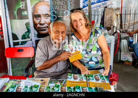 Prison Survivor Chum Mey Posiert Mit EINEM weiblichen Tourist Mit Seinem Buch Namens "Survivor" Im Tuol Sleng Genocide Museum, Phnom Penh, Kambodscha. Stockfoto