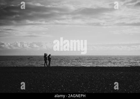 BRIGHTON, Großbritannien - 03.November 2019: Reste von Brighton Pier. Die Silhouetten, die laufen am Strand, Wellen erzeugen Wellen am Ufer, Ocean Spa Stockfoto