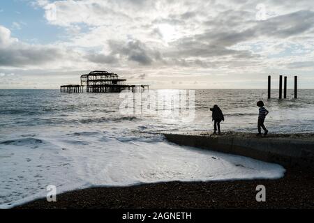 BRIGHTON, Großbritannien - 03.November 2019: Reste von Brighton Pier. Die Silhouetten, die laufen am Strand, Wellen erzeugen Wellen am Ufer, Ocean Spa Stockfoto