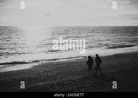 BRIGHTON, Großbritannien - 03.November 2019: Reste von Brighton Pier. Die Silhouetten, die laufen am Strand, Wellen erzeugen Wellen am Ufer, Ocean Spa Stockfoto