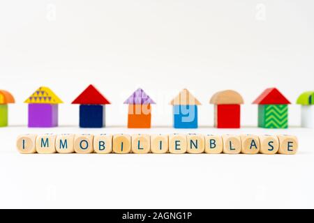 Holzblock mit Buchstaben sagen "immobilienblase" (Deutsch für Real Estate Bubble) vor bunten Spielzeug Häuser Stockfoto