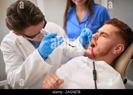 Männliche Patienten zum Zahnarzt in der zahnmedizinischen Stuhl mit Zahnschmerzen Stockfoto