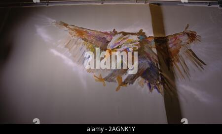 Künstler Designer zieht ein Adler an der Wand. Handwerker Dekorateur malt mit Acryl öl Farbe. Maler Maler gekleidet in Lack auftragen. Indoor. Stockfoto
