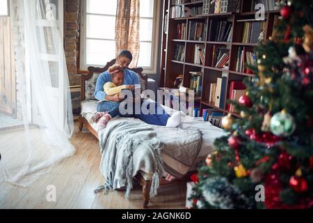 Lächelnd Vater und Tochter genießen Weihnachten Morgen lesen Fairy Tail Stockfoto