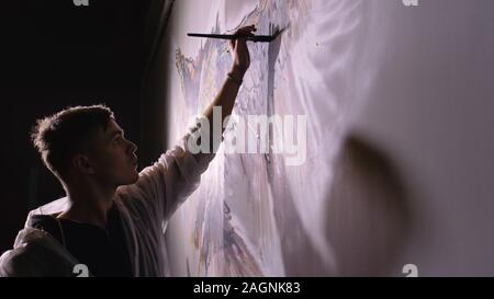 Künstler Designer zieht ein Adler an der Wand. Handwerker Dekorateur malt mit Acryl öl Farbe. Maler Maler gekleidet in Lack auftragen. Indoor. Stockfoto