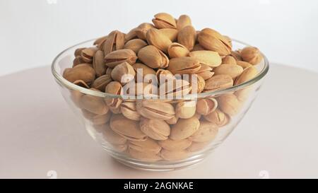 Muttern pistache Drehen sind auf eine Tabelle in einer Platte. Snack in durchsichtigen Teller auf einem isolierten weißen Hintergrund drehen sich bewegt. Stockfoto