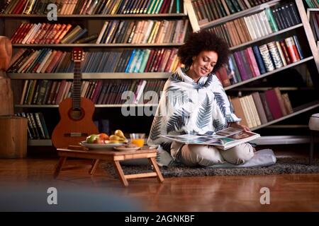 Junge Frau im großen Buch suchen in Zimmer mit Büchern Stockfoto