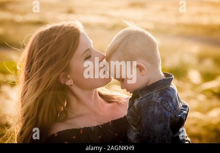 Mama küsst ihr kleiner Sohn auf die Stirn. Stockfoto