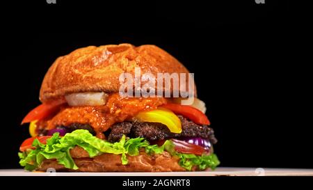 Handwerk Burger ist Kochen. Bestehen: rote Sauce salsa, Salat, rote Zwiebel, Gurke, Käse, Chili, Paprika, Bun- und marmoriertes Fleisch Rindfleisch. Stockfoto