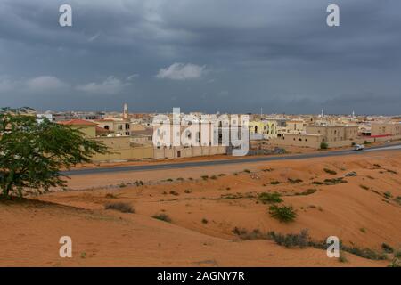 'Ras Al Khaimah, RAK/Vereinigte Arabische Emirate - 12/18/2019: Desert Storm clouds mit Fett verbrannt orange farbigem Sand gegenübergestellt und grün hinterlegt Flora Stockfoto