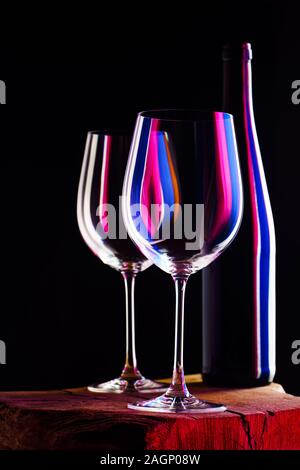 Zwei leere Gläser Rotwein mit Flasche auf Holztisch und dunklen Hintergrund. Intime Atmosphäre. Romantik Konzept Stockfoto