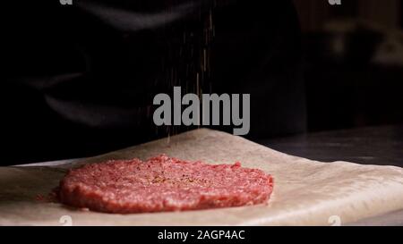 Kochen macht Fleisch Medaillons für Burger. Koch in schwarz Handschuhe macht Schnitzel essen. Die koteletts sind in Stahl Ring in eine noch Medaillon eingeebnet. Stockfoto