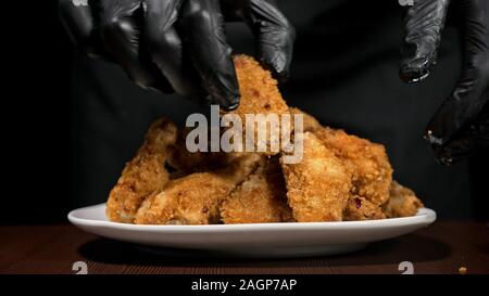 Cool schöne Frische saftige gekocht Chicken Wings in Panade. Buffalo Wings Spread auf Essen in weiße Platte. Kochen mit Friteuse Fry Maschine. Stockfoto