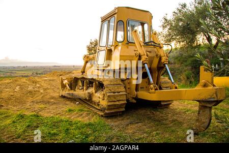 Einen gelben Bulldozer ist das Arbeitspferd der landwirtschaftlichen Nutzflächen. Diese alte Maschine sitzt schlafend Warten auf die nächste Aufgabe (s). Stockfoto