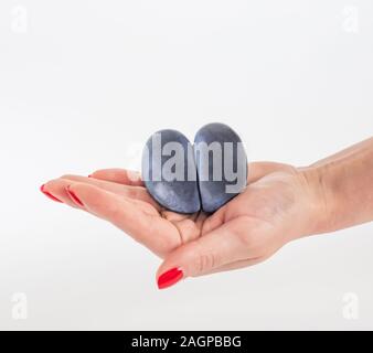 Trendy Hässliches Essen Konzept. Lila hässlich Pflaume in der Hand einer Frau, die auf einem weißen Hintergrund. Obst mit Herz Form. Das Problem von Speiseresten. Stockfoto