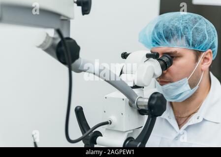 Arzt Mikroskop. Zahnarzt ist die Behandlung von Patienten in der modernen zahnmedizinischen Büro. Die Bedienung erfolgt mittels Fangdamms durchgeführt. Client wird eingefügt und wiederhergestellt Stockfoto