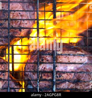 Paar Stücke etwas verbranntem Fleisch auf verkohlte Gitter mit Feuer und Rauch unter Stockfoto