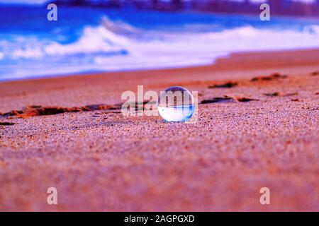 Nahaufnahme einer transparenten Kugel in einem rosa Sand Strand bei Sonnenuntergang Stockfoto