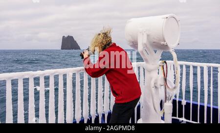 Eine gefrorene Schiff Deck auf See in der Antarktis mit Eis auf dem Geländer und ein Suchscheinwerfer, während eine Fotografin Fotos nimmt. Stockfoto