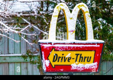 Die Zeichen für eine Drive-thru an einem McDonald's Fast Food Restaurant in Kanada hat eine Schicht Schnee nach einem windigen Schneesturm. Stockfoto