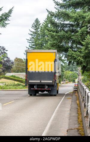 Big Rig gelb Tag cab Semi Truck für die lokalen Lieferungen Transport von kommerziellen Ladung in Box Anhänger mit Aufzug auf der Rückseite, auf die City Road wit Stockfoto