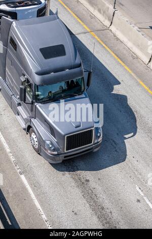Big Rig dunkelgrau Motorhaube leistungsfähige Semi Truck mit hoher Kabine transportieren Tiefkühlprodukte und gekühlte kommerziellen Ladung im Kühlschrank Auflieger läuft Stockfoto