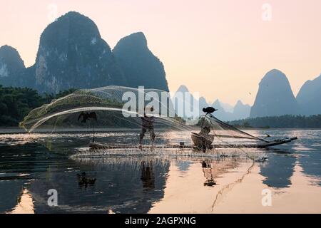 Xingping, China - November 5, 2019: Porträt einer Kormoran Fischer bei Sonnenuntergang mit einer traditionellen Fangmethoden die Fische im Fluss zu fangen Stockfoto