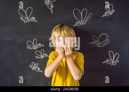 Der Junge wird durch Moskitos auf einem dunklen Hintergrund gebissen. Auf der Tafel mit Kreide gemalt Moskitos Stockfoto