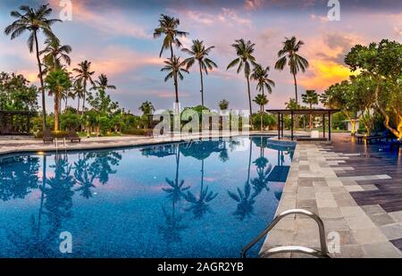 Großer Pool mit Palmen bei Sonnenuntergang auf Bali, Indonesien Stockfoto