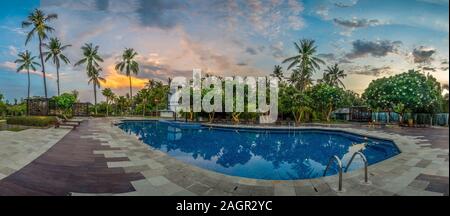 Großer Pool mit Palmen bei Sonnenuntergang auf Bali, Indonesien Stockfoto