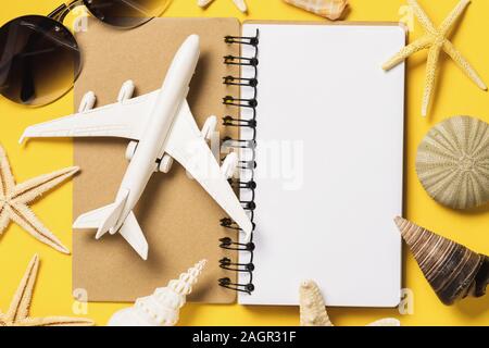 Ein Spielzeug Flugzeug auf einem Notebook mit Kopieren von Muscheln umgeben. Ferienhäuser Planung Konzept Stockfoto