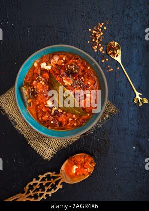 Pomodoro, Arabiatta oder Marinara Sauce. Red pasta Sauce in eine blaue Schüssel, mit einem Holzlöffel und Chili Flocken, im rustikalen Stil präsentiert. Stockfoto