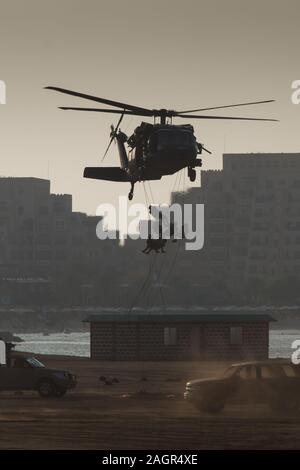 Militärischen Kampf und Krieg mit dem Hubschrauber in das Chaos und Zerstörung zu fliegen. Soldaten aus Seil auf den Boden von Chopper aussetzen. Militärisches Konzept Stockfoto