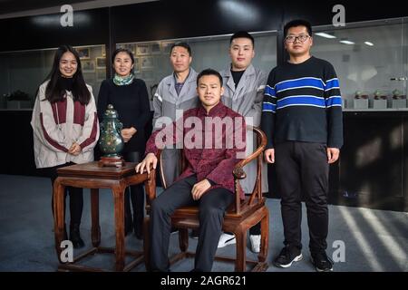 (191221) - Peking, 21. Dez., 2019 (Xinhua) - Guo Weijun (vorne) Posen für Fotos mit seine Lehrlinge in Peking, der Hauptstadt von China, Dez. 17, 2019. Als eine der acht einzigartige Kunst und Handwerk im alten Peking, Jade Carving wurde als nationale immateriellen Kulturerbes im Jahr 2008 gekrönt. Die Technik, mit Gold und Silber Inlay, besonders genießt einen guten Ruf für hohe Kunst, wissenschaftliche und historische Werte. Guo Weijun, einem renommierten Handwerksbetrieb in Gold und Silber mit Intarsien Jadeschnitzerei, fördert und innovative diese Technik so, dass bekannt und von mehr Menschen und die begünstigt werden Stockfoto