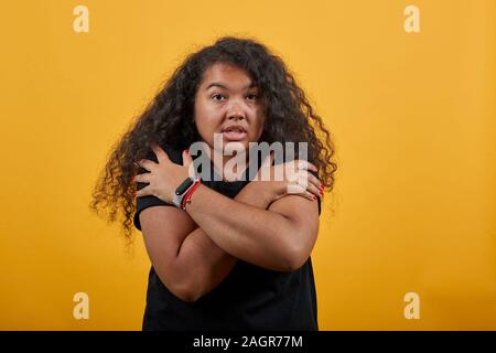 Afro-amerikanischer Junge Frau mit Übergewicht umarmen sich, halten die Hände gekreuzt Stockfoto