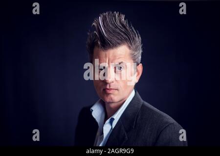 Handsone Mann mit Mohawk tragen Anzug vor schwarzem Hintergrund. Stockfoto
