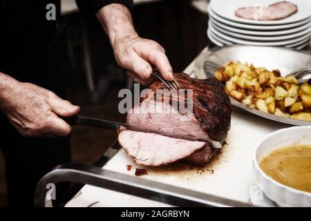 Koch ist Schneiden Beefsteak mit Schinkenmesser, getönten Bild Stockfoto