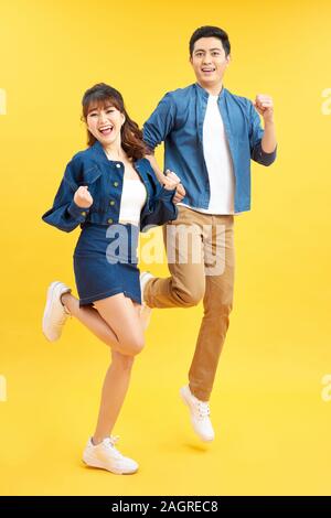 Volle Länge Körper Größe seiner er ihr, daß sie schöne attraktive Crazy Funky fröhliches Paar springen in die Luft, das Spaß macht Freude auf Yello isoliert Stockfoto