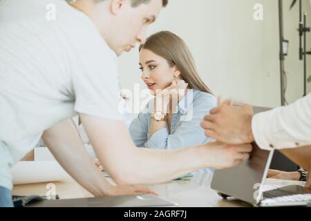 Einbindung in den Workflow. Eine junge weibliche Mitarbeiter beschäftigt mit der Arbeit und ist nicht durch den Lärm und die Arbeit der anderen Kollegen abgelenkt. Stockfoto
