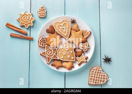 Ingwer cookies mit Sahnehäubchen auf eine Platte auf einem blauen Hintergrund Holz dekoriert. Ansicht von oben Stockfoto
